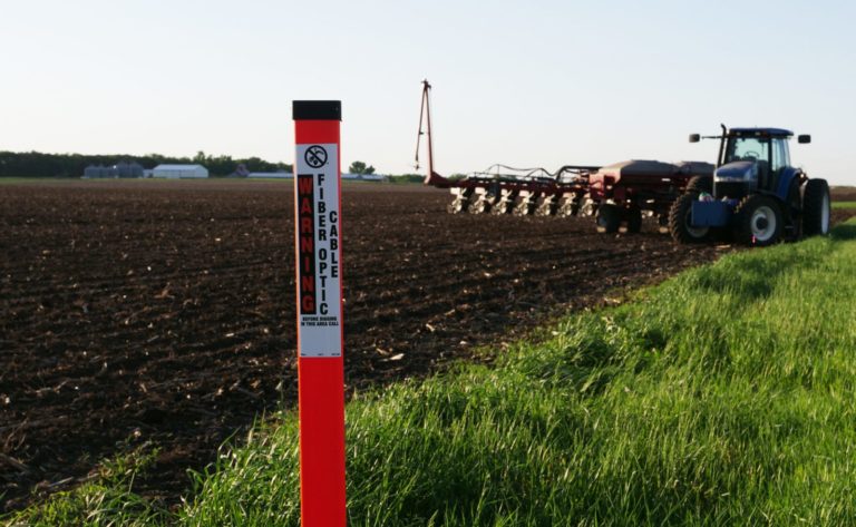 Warning Fiber Optic Cable TriView next to a field with a tractor